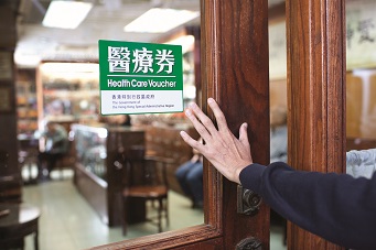 This photo demonstrates an elder's entry into an clinic with the logo of the Health Care Voucher Scheme.