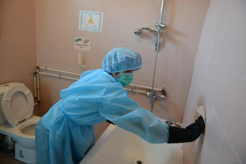 An officer of the Food and Environmental Hygiene Department in personal protective clothing undertakes necessary disinfection and cleansing of contaminated sites and objects.