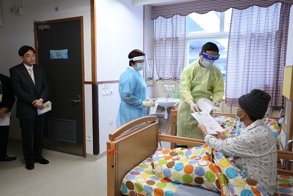 The Secretary for Food and Health, Dr Ko Wing-man (left), watches as CHP officers serve quarantine orders to three inmates.